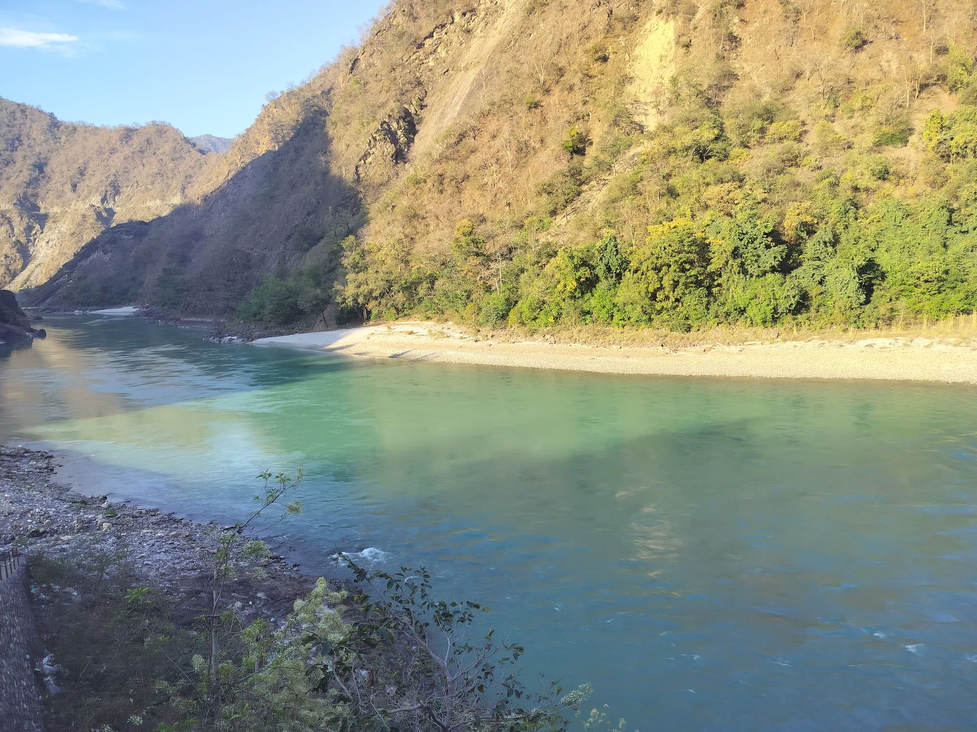 Blue-green Ganga flowing past a white sand beach below dry, steep hillsides at Kaudiyala on the road from Rishikesh to Devprayag