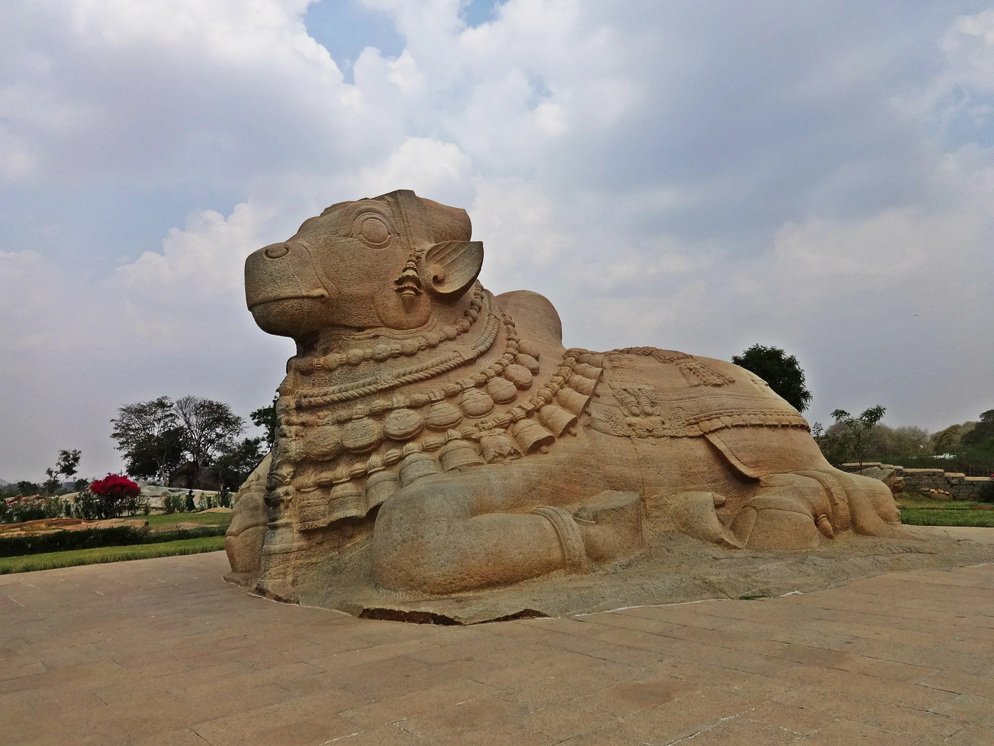 The giant monolithic Nandi bull at Lepakshi under a cloudy sky, a stop on a self-drive car rental in Bangalore day trip