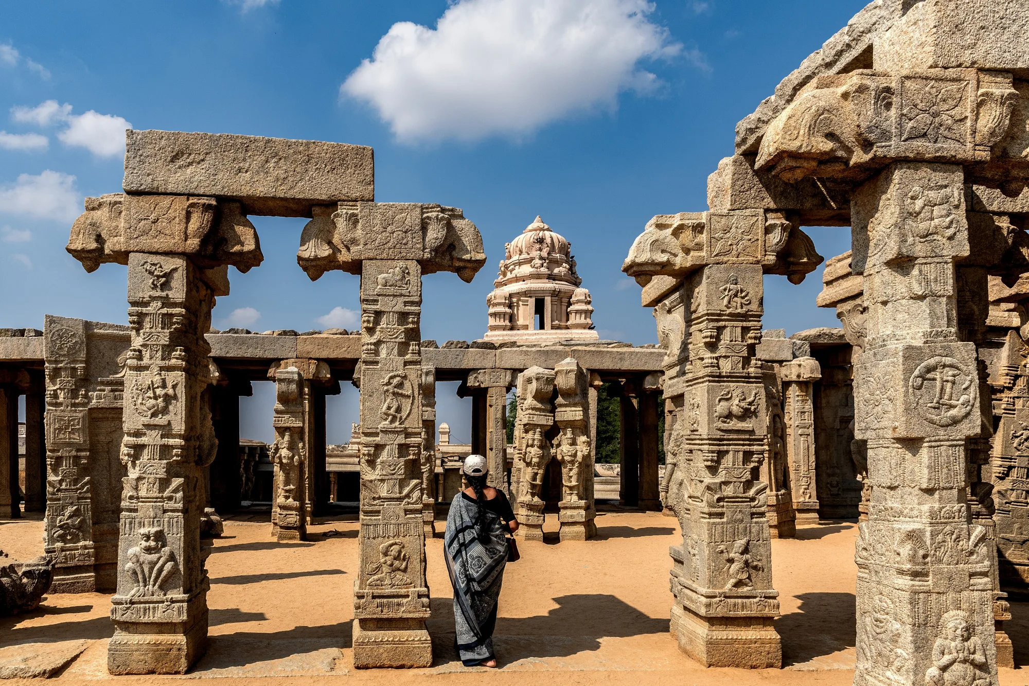 Carved granite pillars of the unfinished Kalyana Mantapa at Lepakshi with the temple tower behind, north of Bangalore