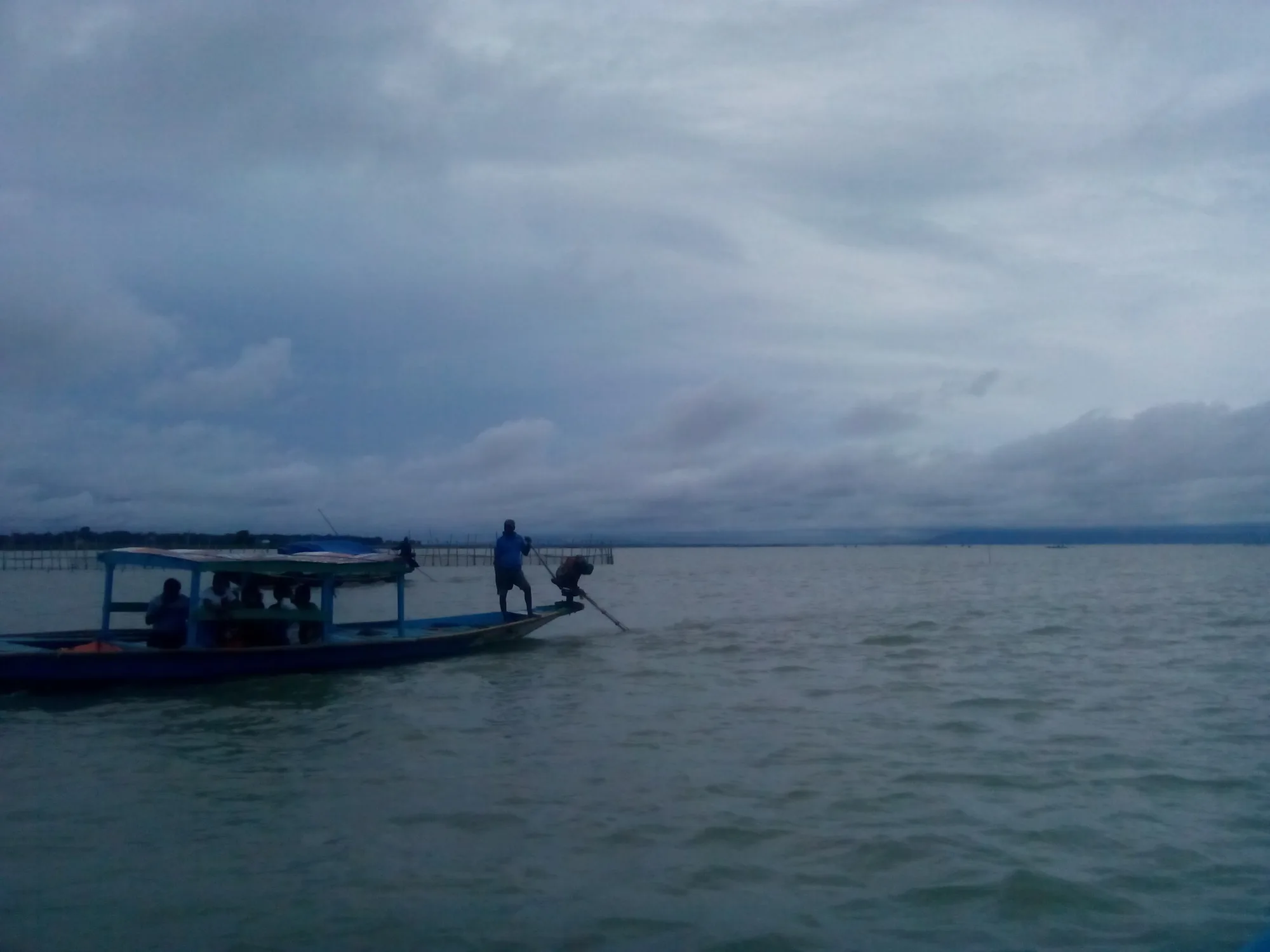 Dolphin-watching boats on open water at Chilika Lake near Satapada, Odisha, under a cloudy sky
