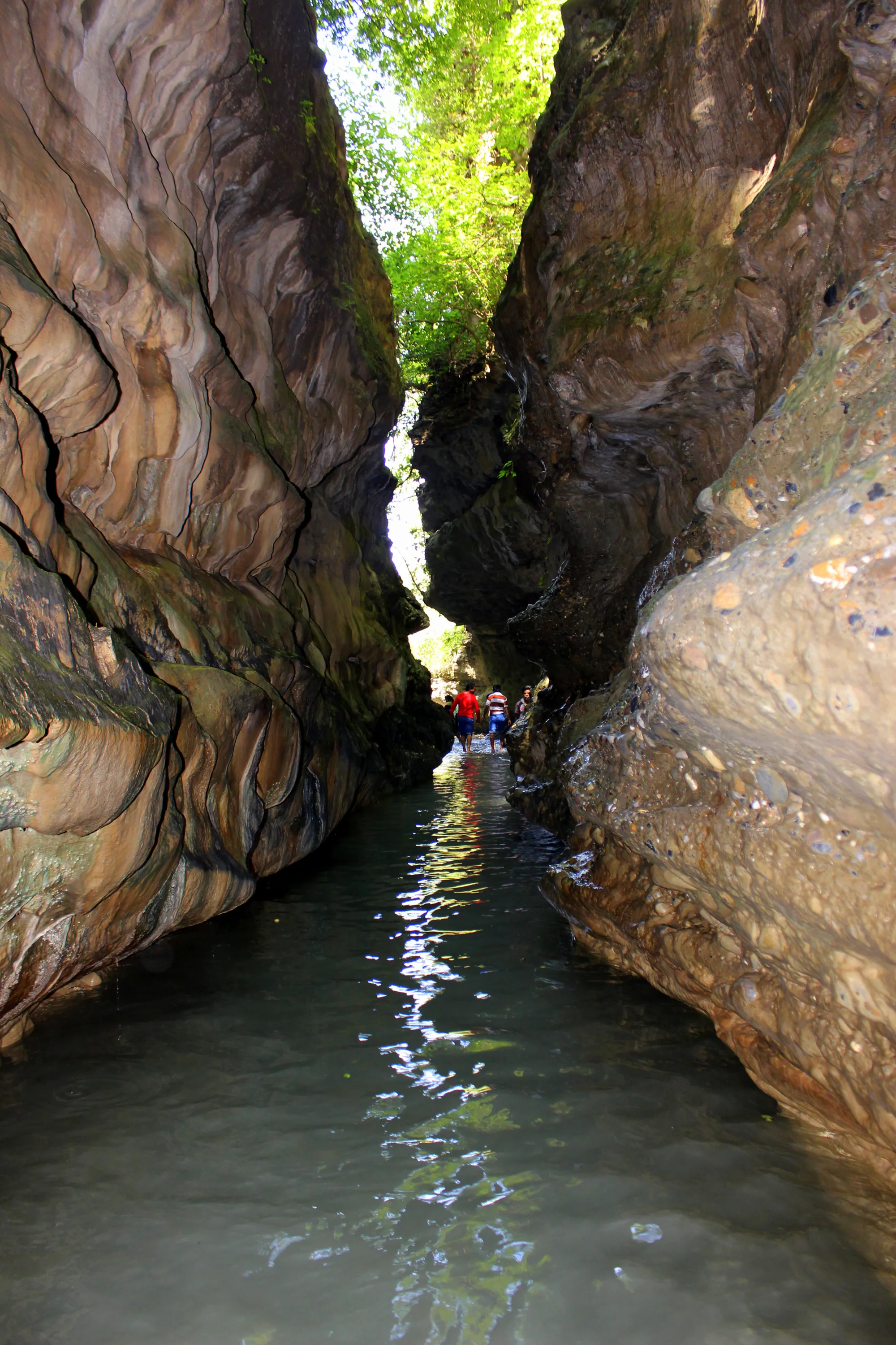 A visitor wading through the narrow rock gorge of Robber's Cave in Dehradun, a short ride on a bike rental in Dehradun