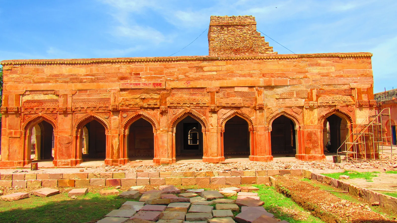 Red sandstone pavilion with a row of pointed arches and a stone path inside Chunar Fort under a blue sky