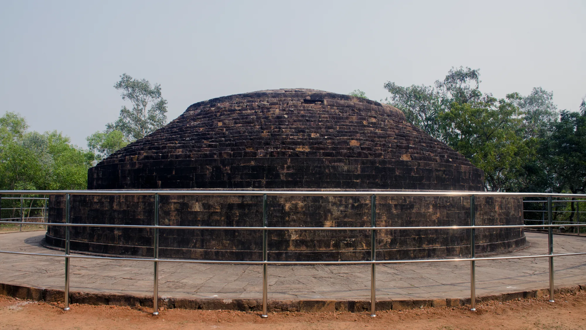 The large round brick main stupa on the hilltop at Lalitgiri in Odisha, surrounded by a metal railing