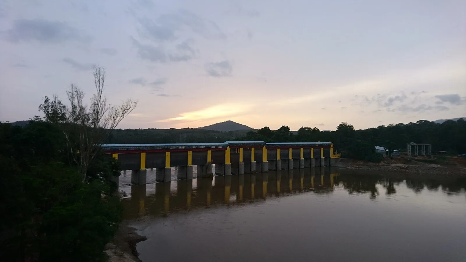 Bhoothathankettu dam across the Periyar River at dusk with forested hills behind