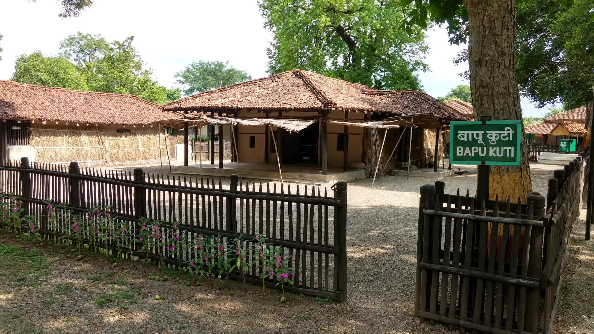 Bapu Kuti hut with tiled roof and wooden fence at Sevagram Ashram, a day trip by car rental in Nagpur