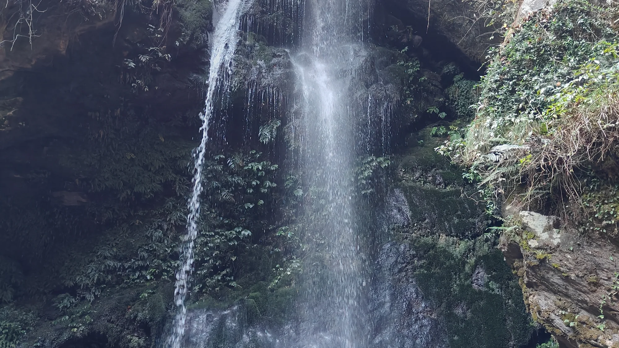 Jibhi waterfall cascading over mossy rock, a short walk from the Banjar road when you ride into Tirthan Valley on a bike rental in Bhuntar
