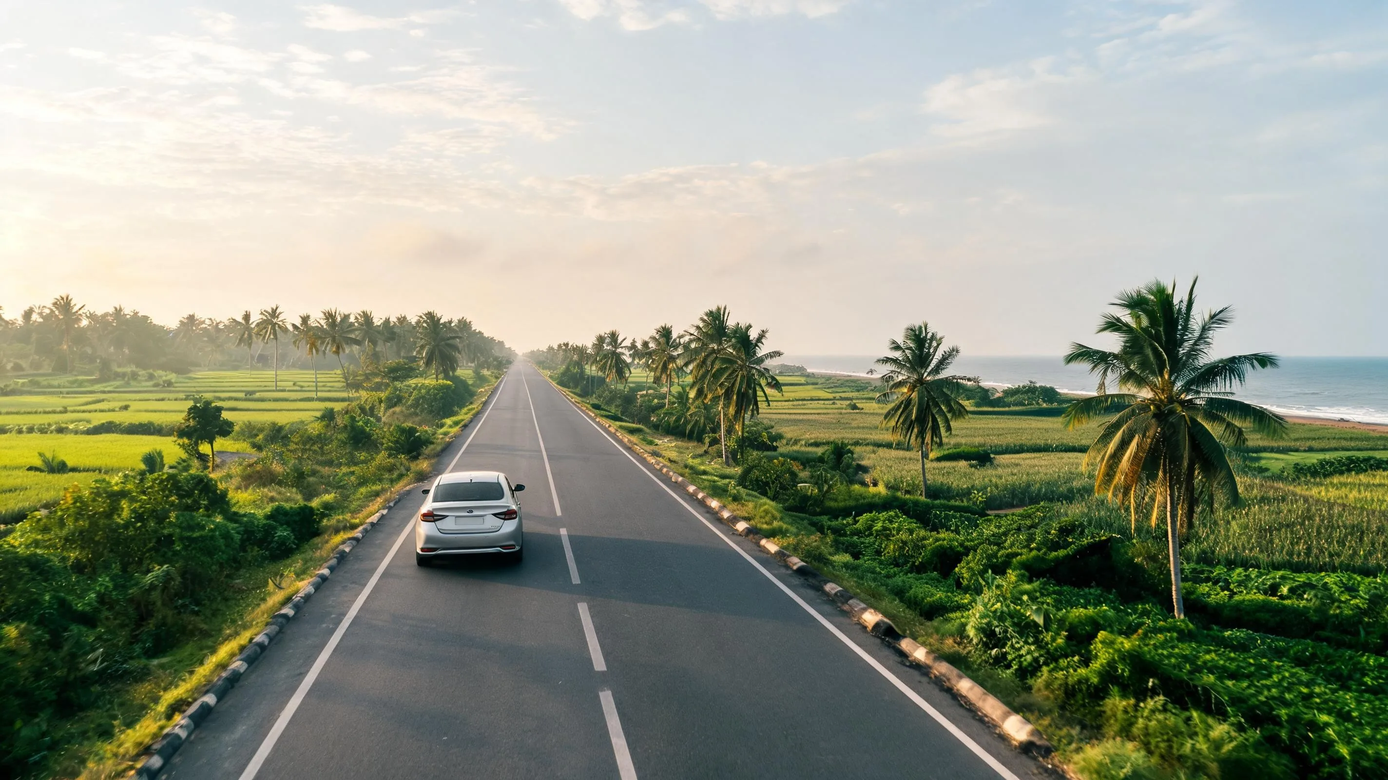 Self-drive rental car on a coastal Odisha highway lined with palms, the kind of road used for car rental in Bhubaneswar trips toward Konark