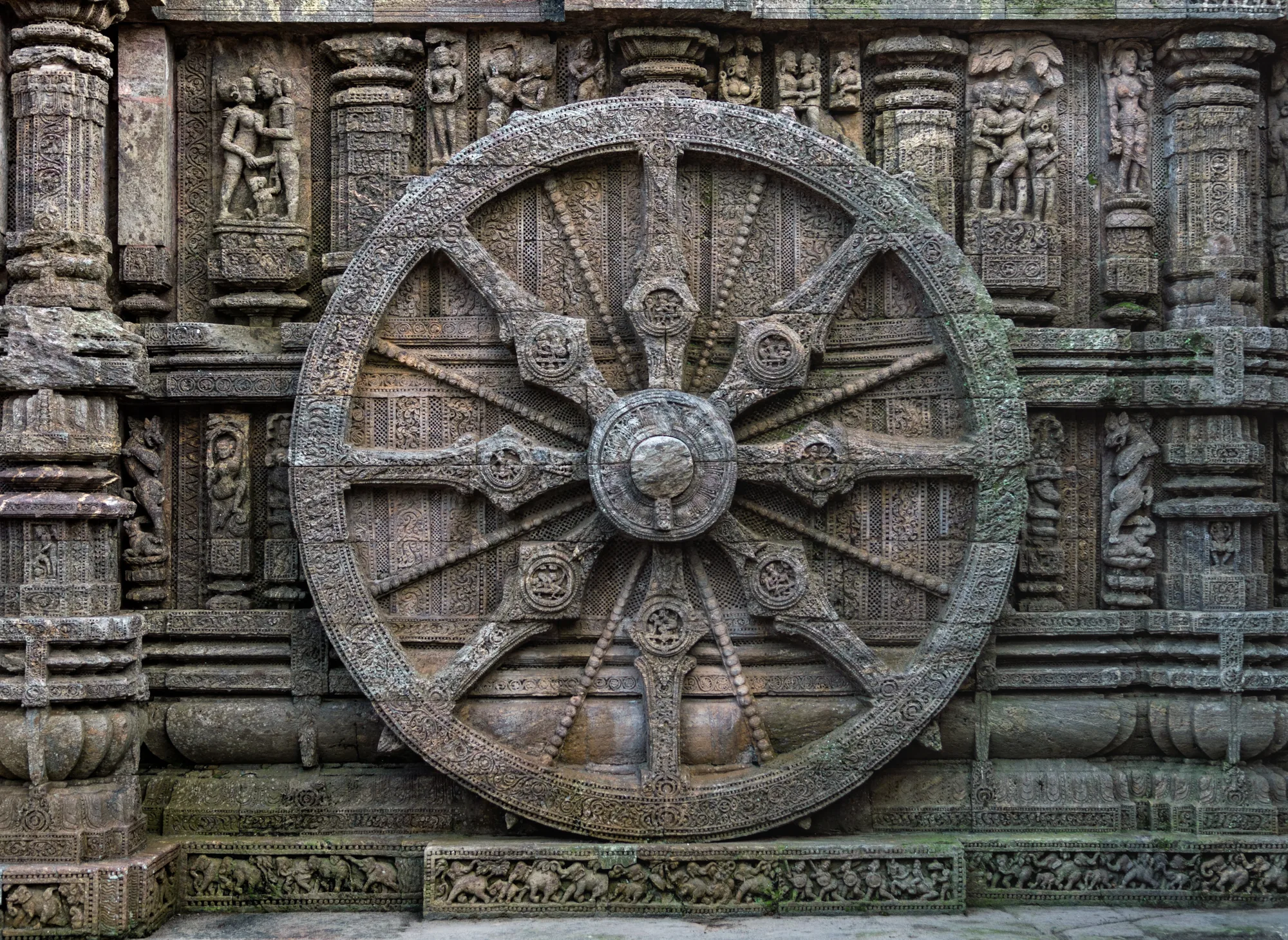 Close-up of a carved stone chariot wheel at Konark Sun Temple, a landmark on a self-drive car rental in Bhubaneswar day trip