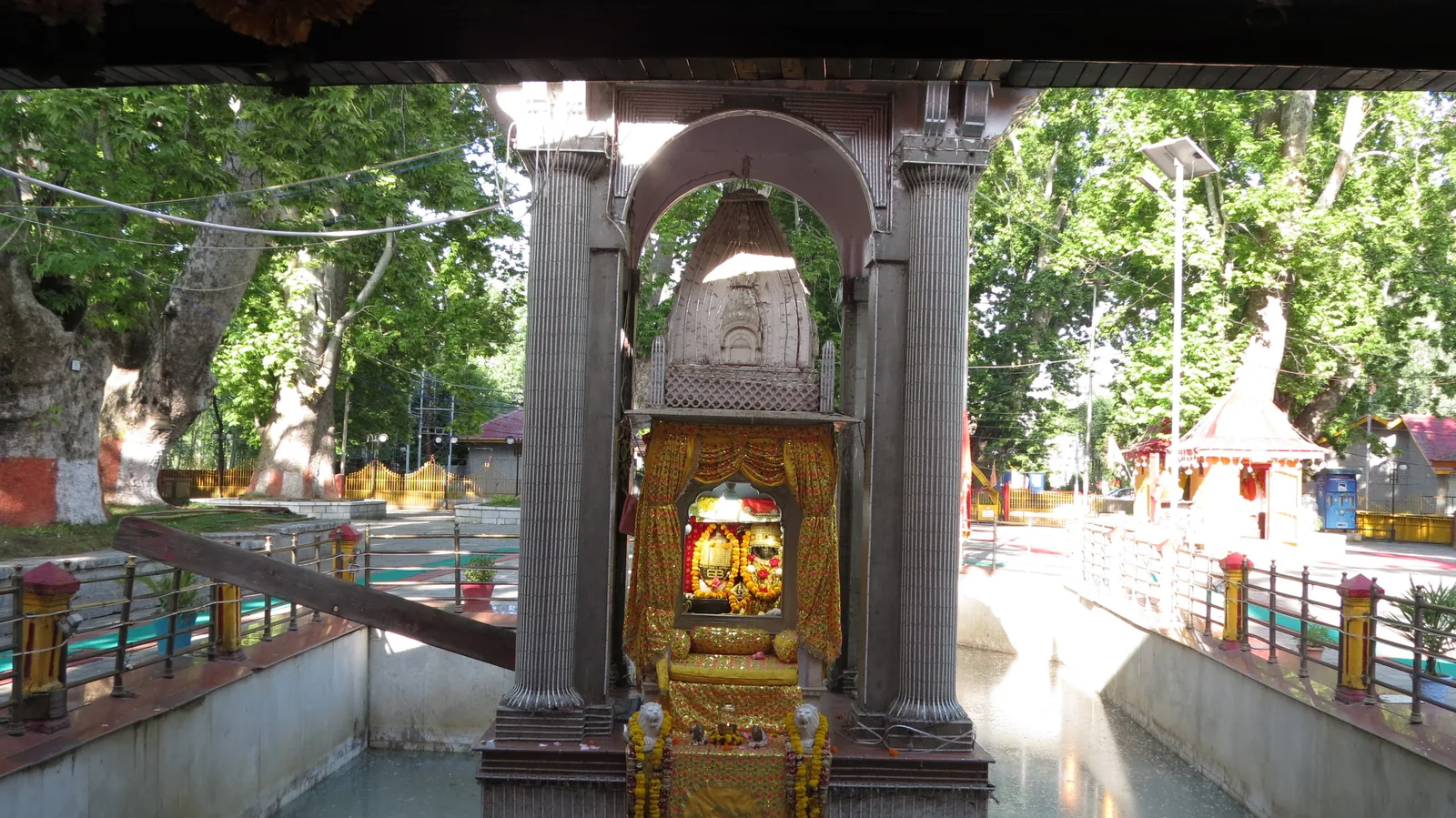 The marble shrine of Kheer Bhawani standing in its sacred spring at Tulmulla, with old chinar trees around the temple courtyard
