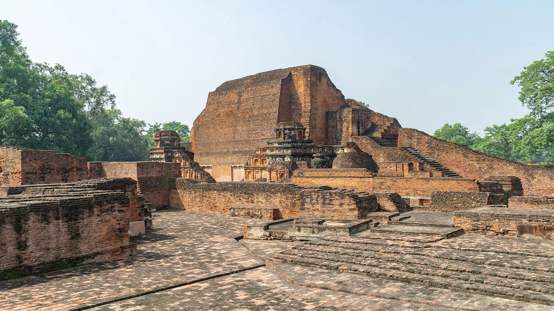 Red-brick Sariputta Stupa and monastery walls at the Nalanda Mahavihara ruins in clear morning light, a day trip by self-drive car rental in Patna
