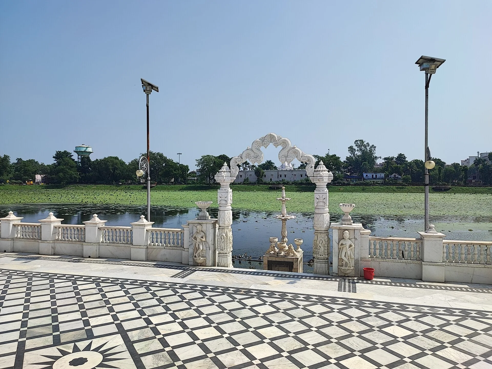 Marble causeway railings and carved arch at Pawapuri Jal Mandir with the lotus tank behind