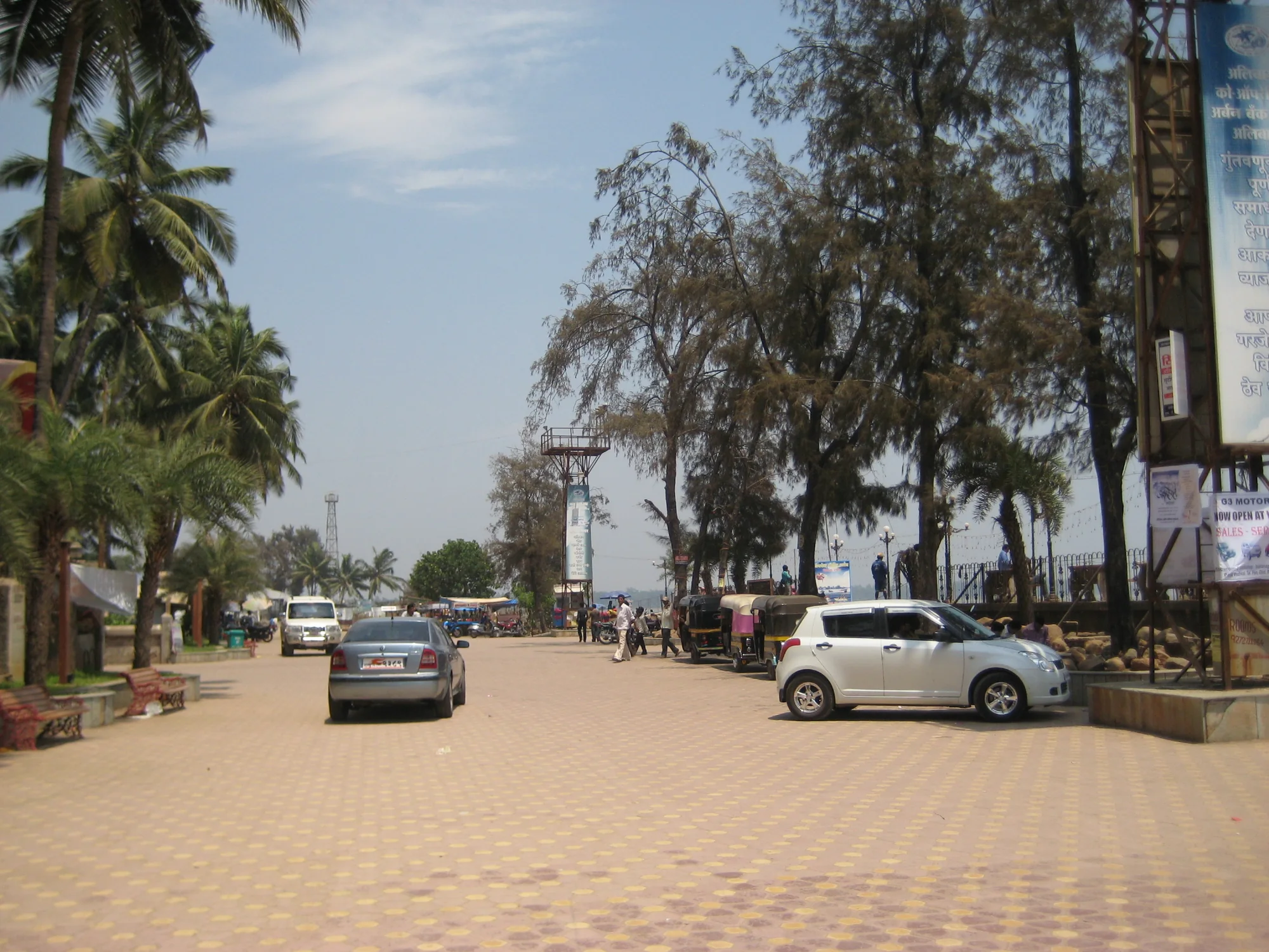 Palm-lined parking plaza near Alibag beach with parked cars, useful after a Mumbai self-drive arrival
