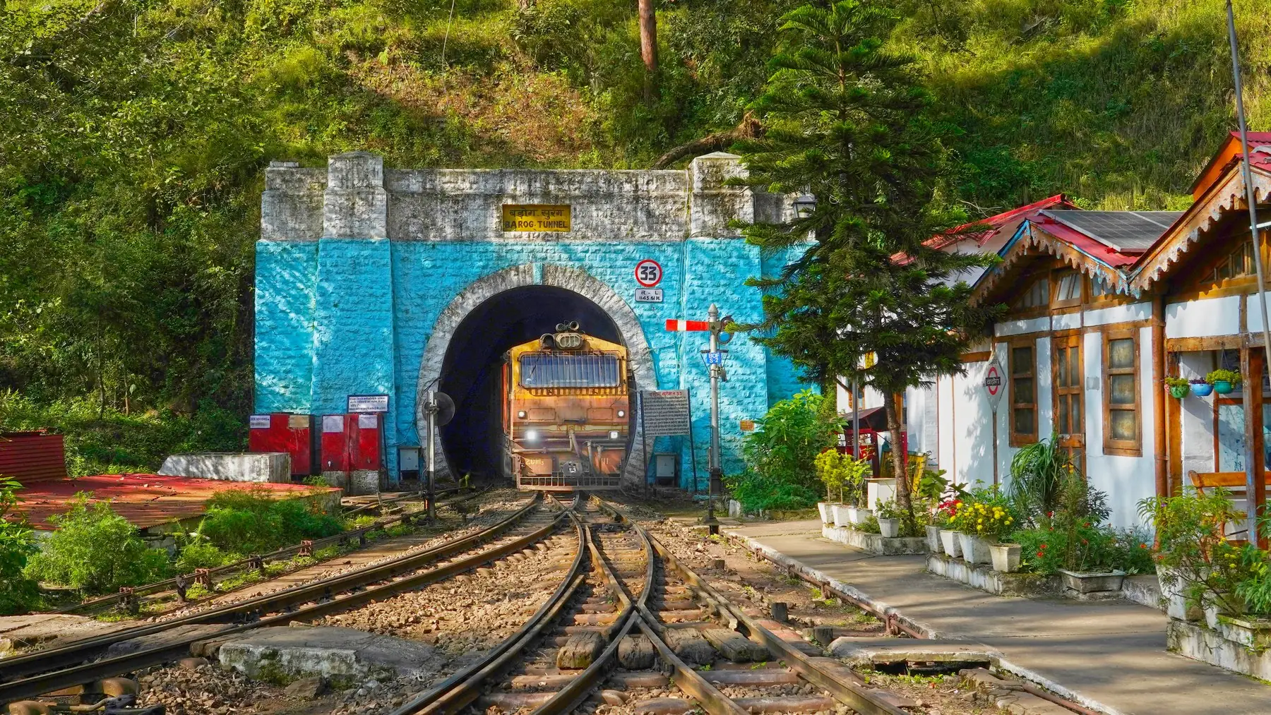 A diesel toy train leaving the blue stone portal of Tunnel 33 at Barog station, a day trip on a bike rental in Chandigarh