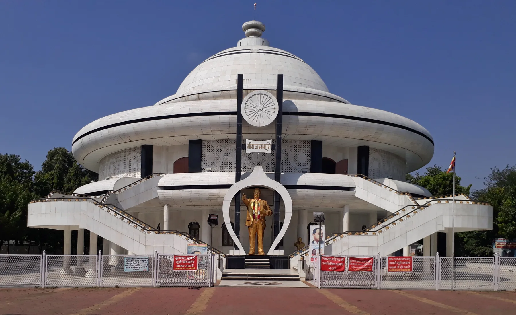 The white circular Bhim Janmabhoomi memorial at Mhow with a golden statue of Dr B. R. Ambedkar at its entrance