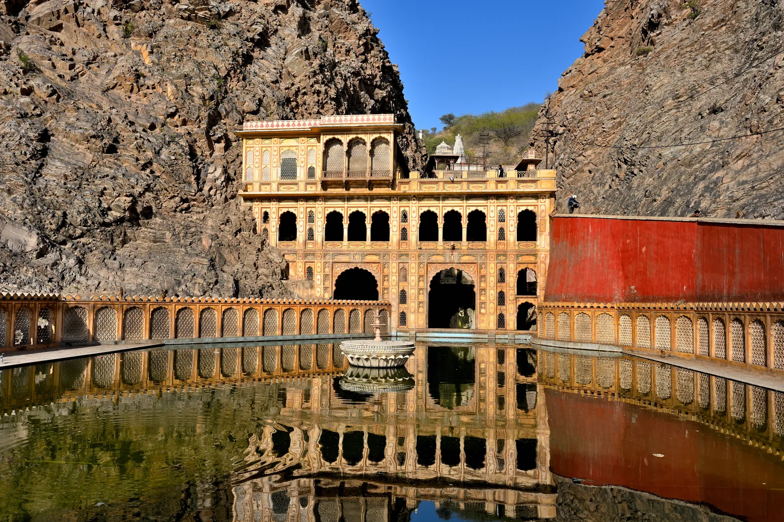 Zanana Kund and pink temple facades at Galta Ji with pilgrims and monkeys near the sacred water tanks