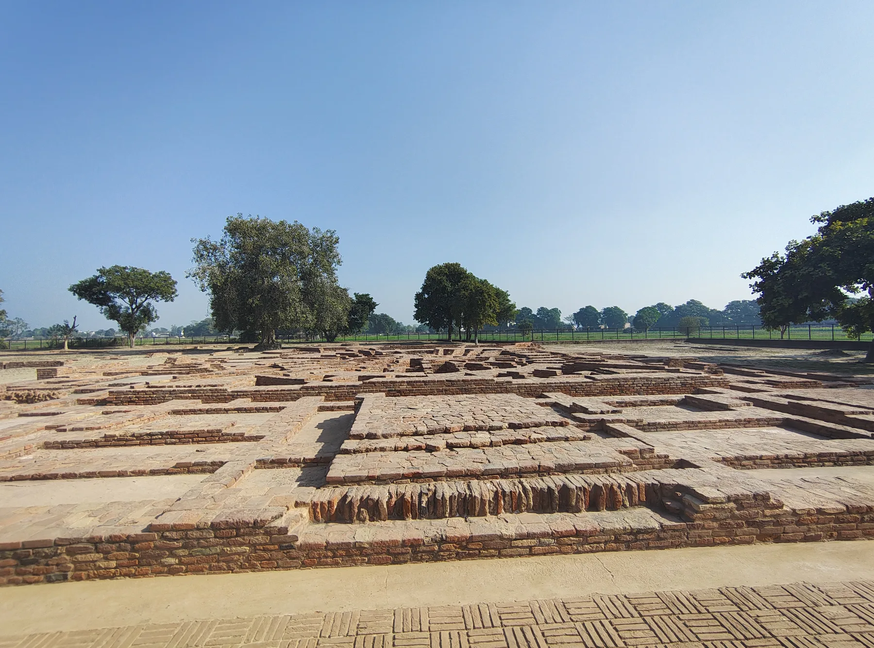Excavated brick foundations of the ancient Buddhist stupa site at Sanghol in Punjab, laid out in rows under a pale sky