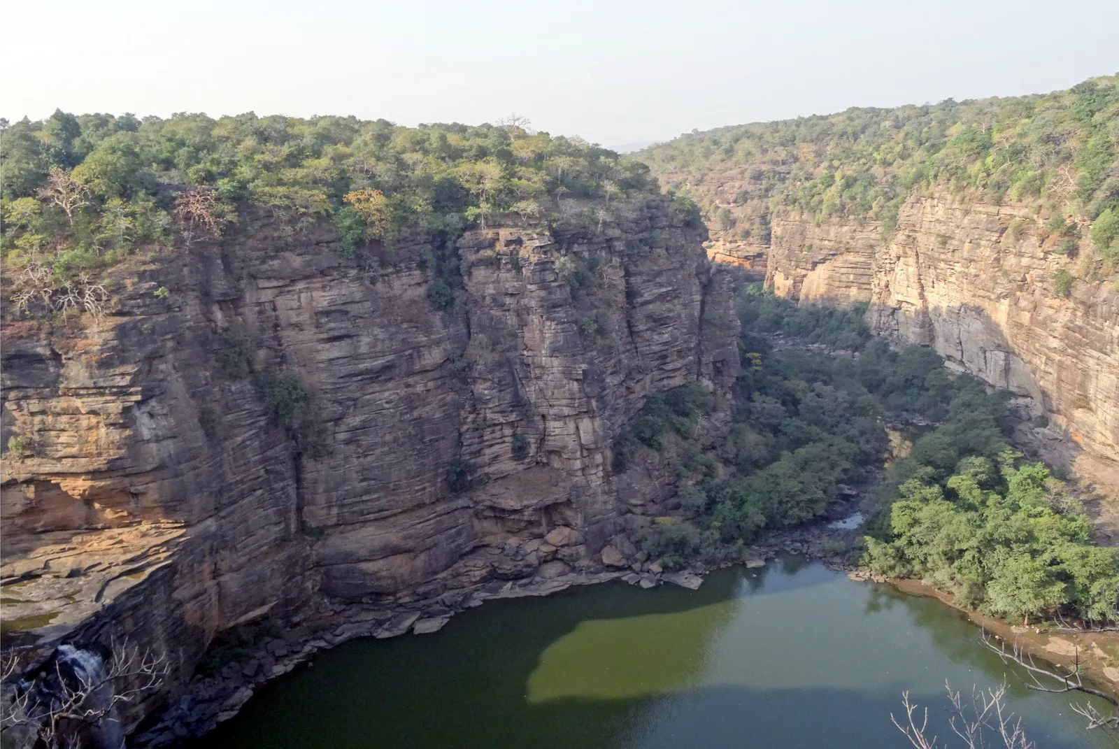 The deep Devdari gorge in October, with layered sandstone walls, a green pool and only a thin stream of water at the foot of the fall