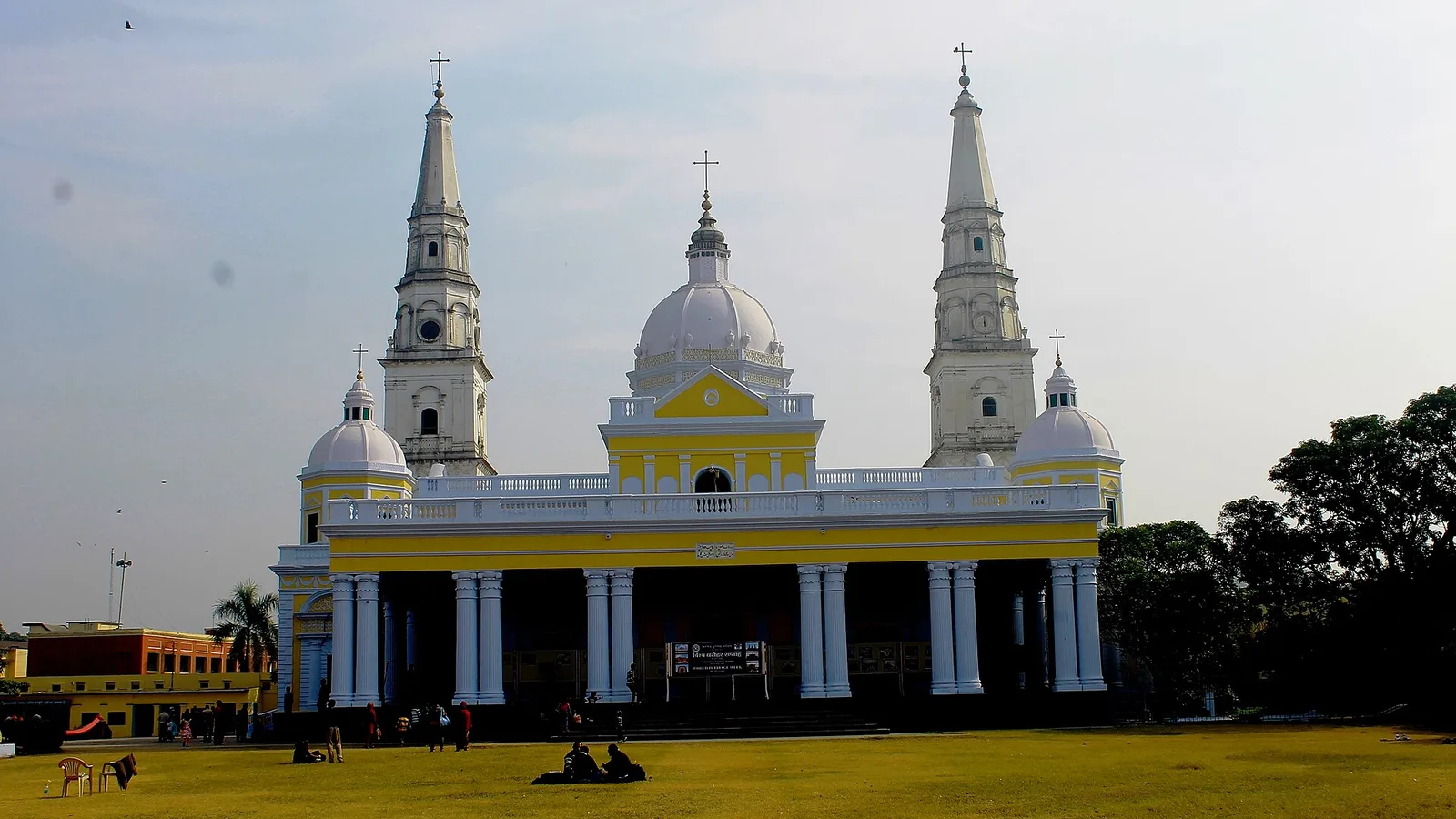 The Basilica of Our Lady of Graces at Sardhana, a yellow and white church with two tall spires and a central dome behind a wide green lawn, a half-day trip by self-drive car rental in Meerut