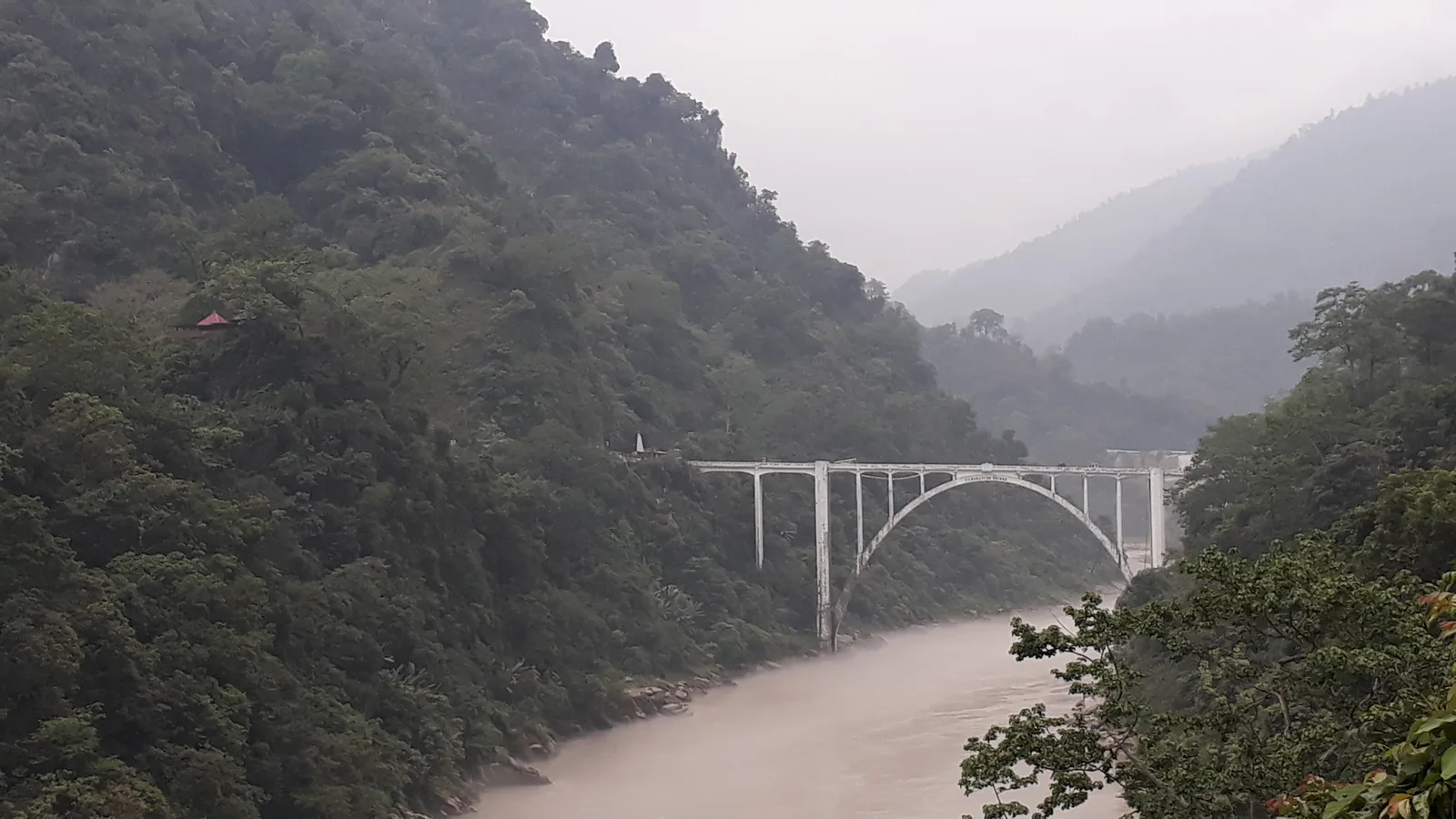 The white arch of the Coronation Bridge spanning the Teesta gorge at Sevoke between forested hills, the first landmark on a Gorumara drive with self-drive car rental in Siliguri