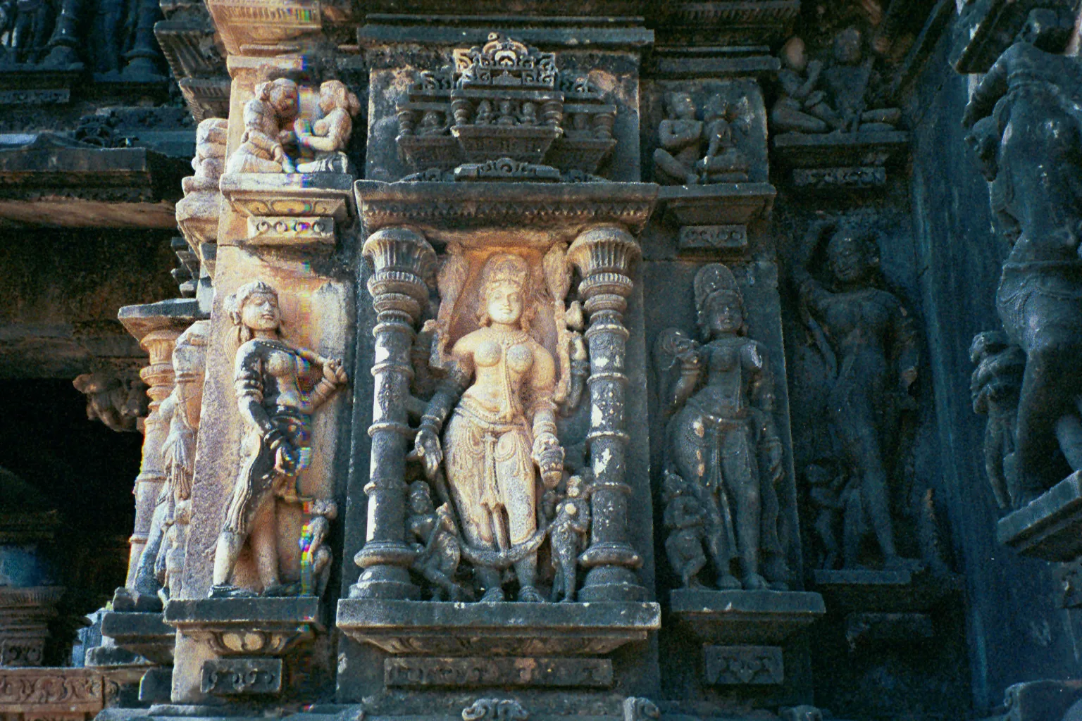 Carved stone figures on the wall of the Ambika Mata temple at Jagat, with a standing goddess in a pillared niche between other female figures