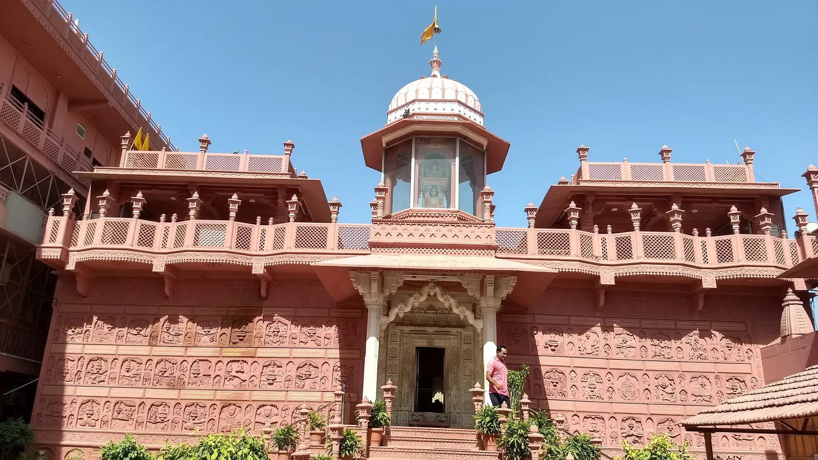 Front of the red sandstone Sanghiji Jain temple in Sanganer, with carved walls, a central white dome and a staircase under a clear blue sky, a stop on a bike rental in Jaipur day ride