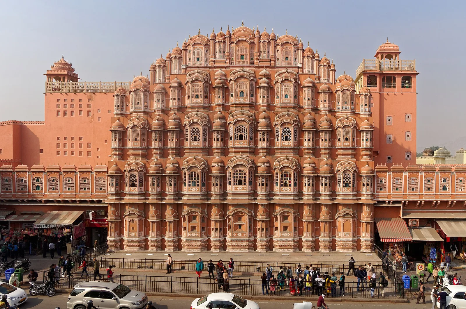 The pink sandstone facade of Hawa Mahal in Jaipur with traffic on the road below