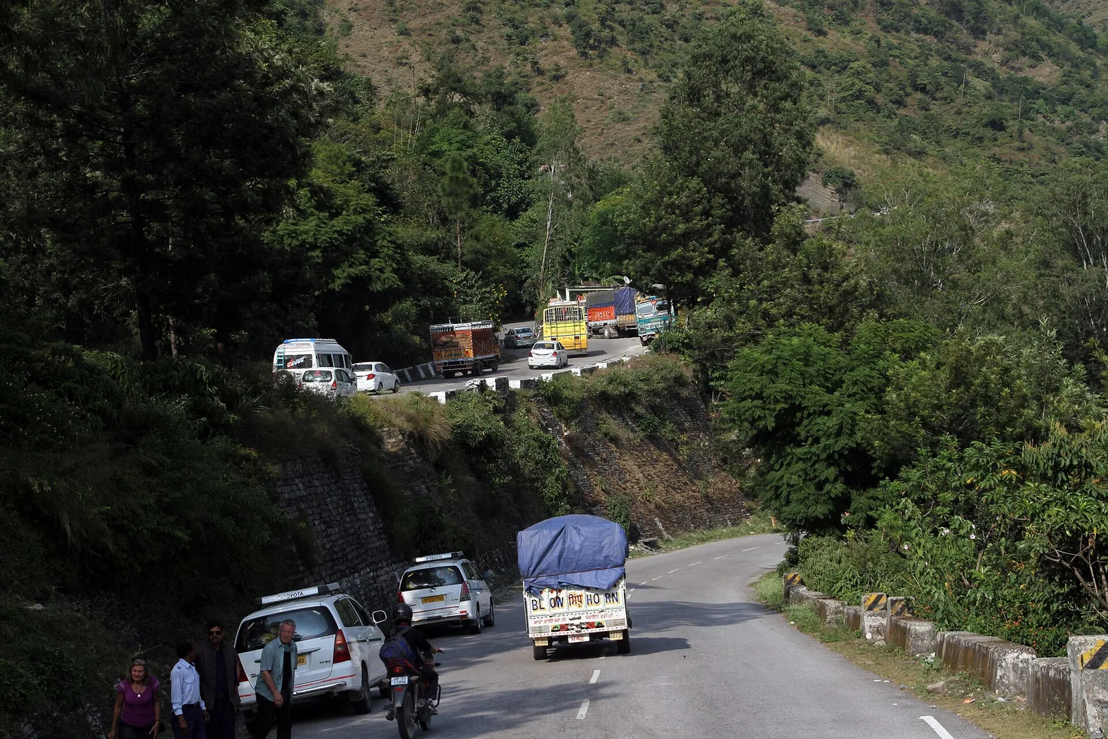 Cars, a truck and a bus queued on a hairpin bend of the Chandigarh-Manali highway above Pandoh dam with forested hills behind