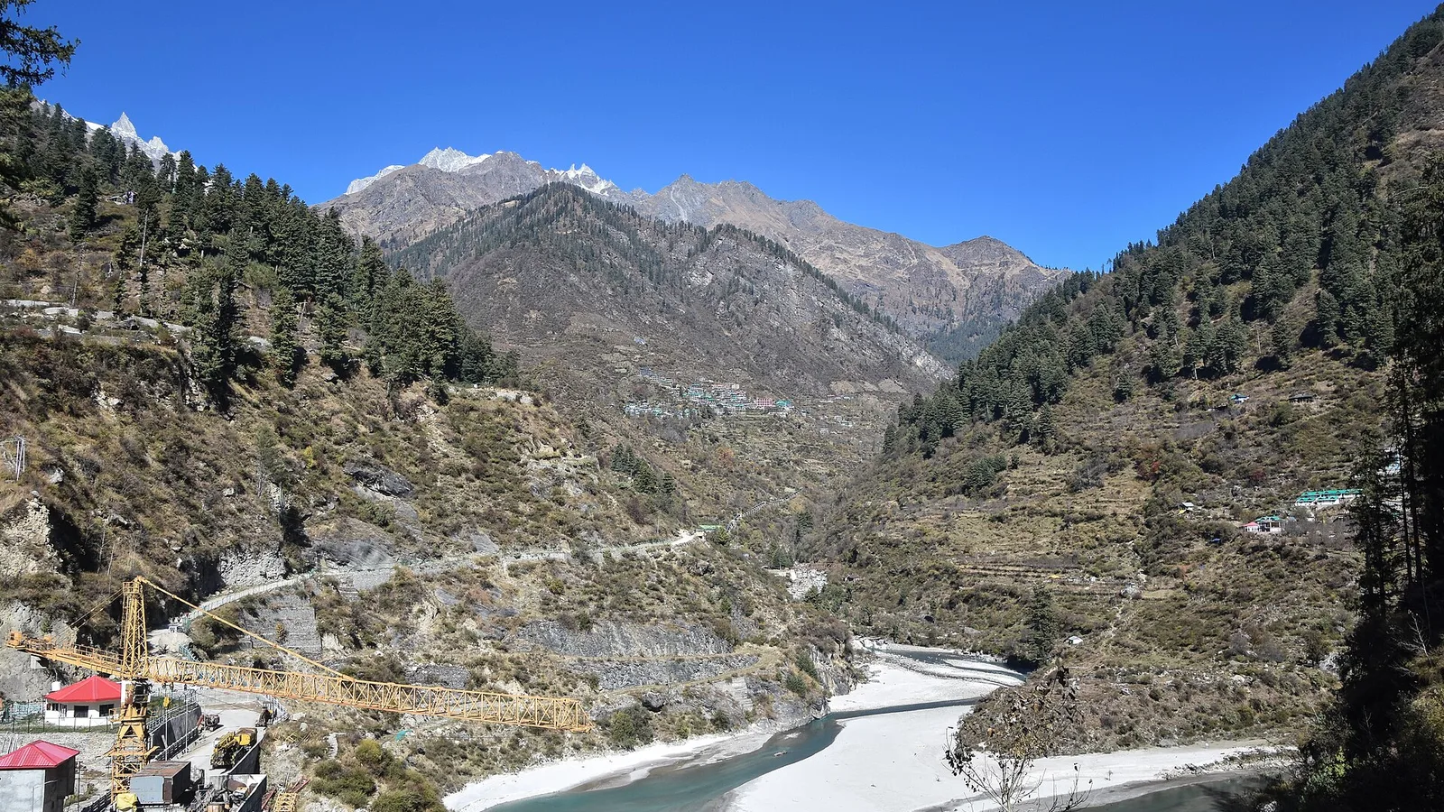 The upper Parvati valley near Tosh in November, with dry brown slopes, pine forest, snow on the far peaks and the river below