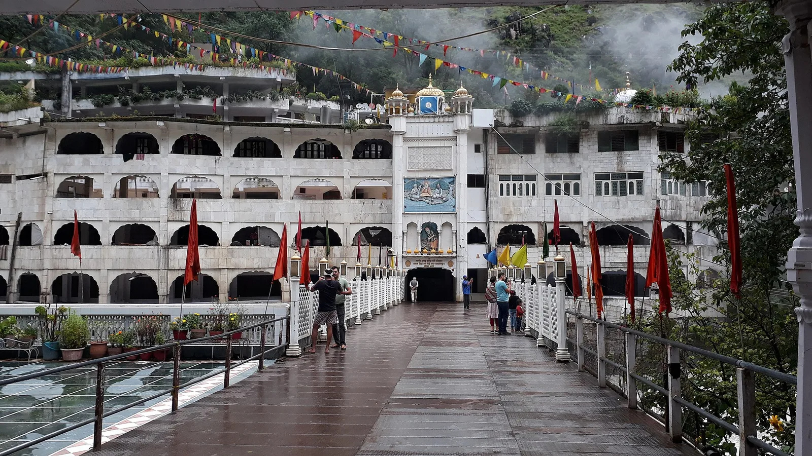 The white gurdwara at Manikaran seen from a footbridge over the Parvati river, decorated with orange flags