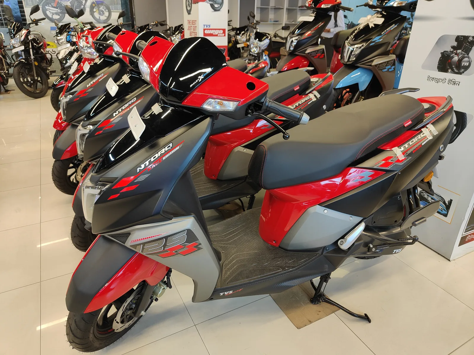 A row of red and black TVS Ntorq 125 scooters parked in a showroom
