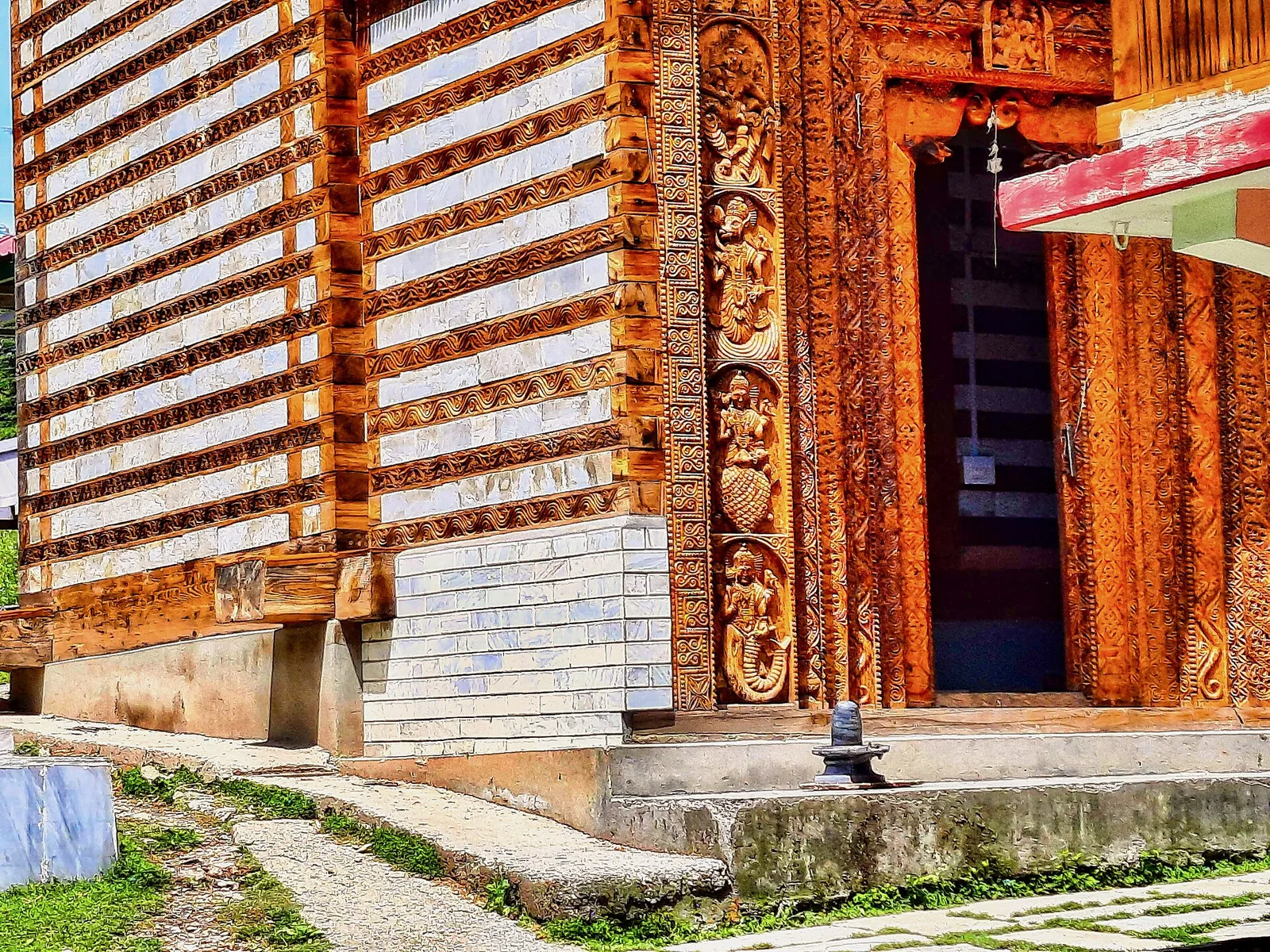 Carved wooden doorway and layered timber and stone walls of the Shangchul Mahadev temple at Shangarh