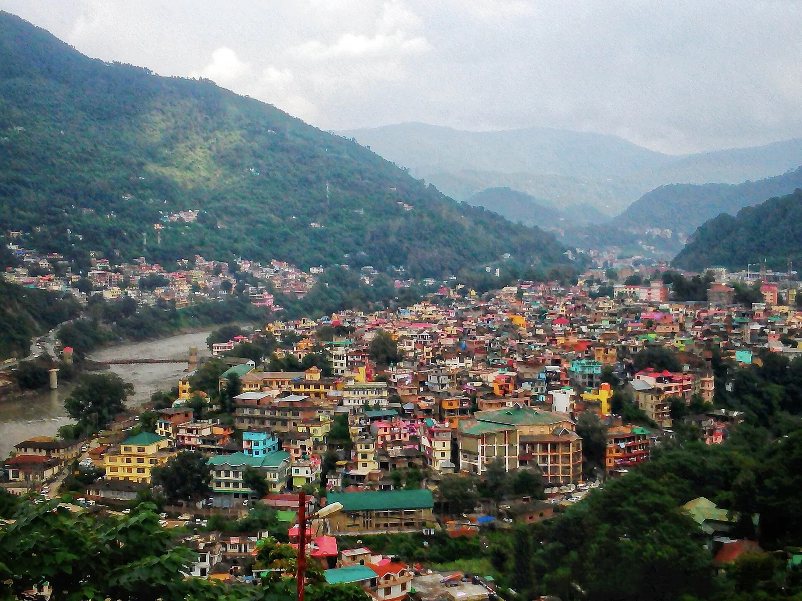 Colourful houses of Mandi town spread along the Beas river valley with forested hills behind